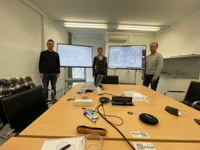 Three people, two surface hub displays and a table
